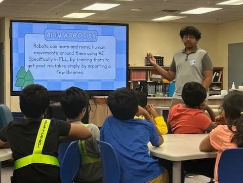 AIforALL volunteer explaining AI in robotics to a group of students at the library