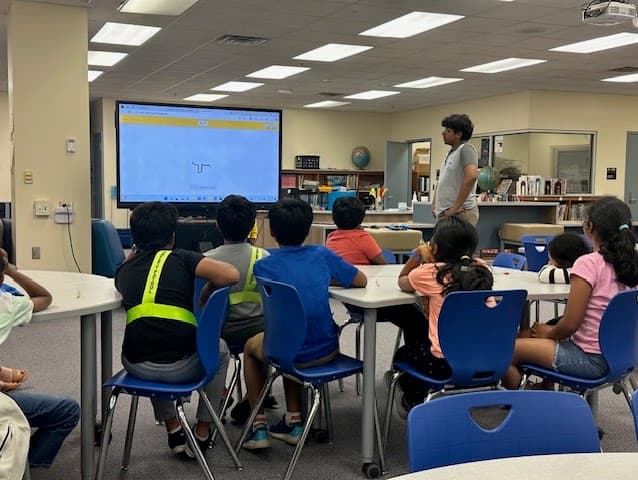 AIforALL volunteer teaching a small library group how AI can generate drawings